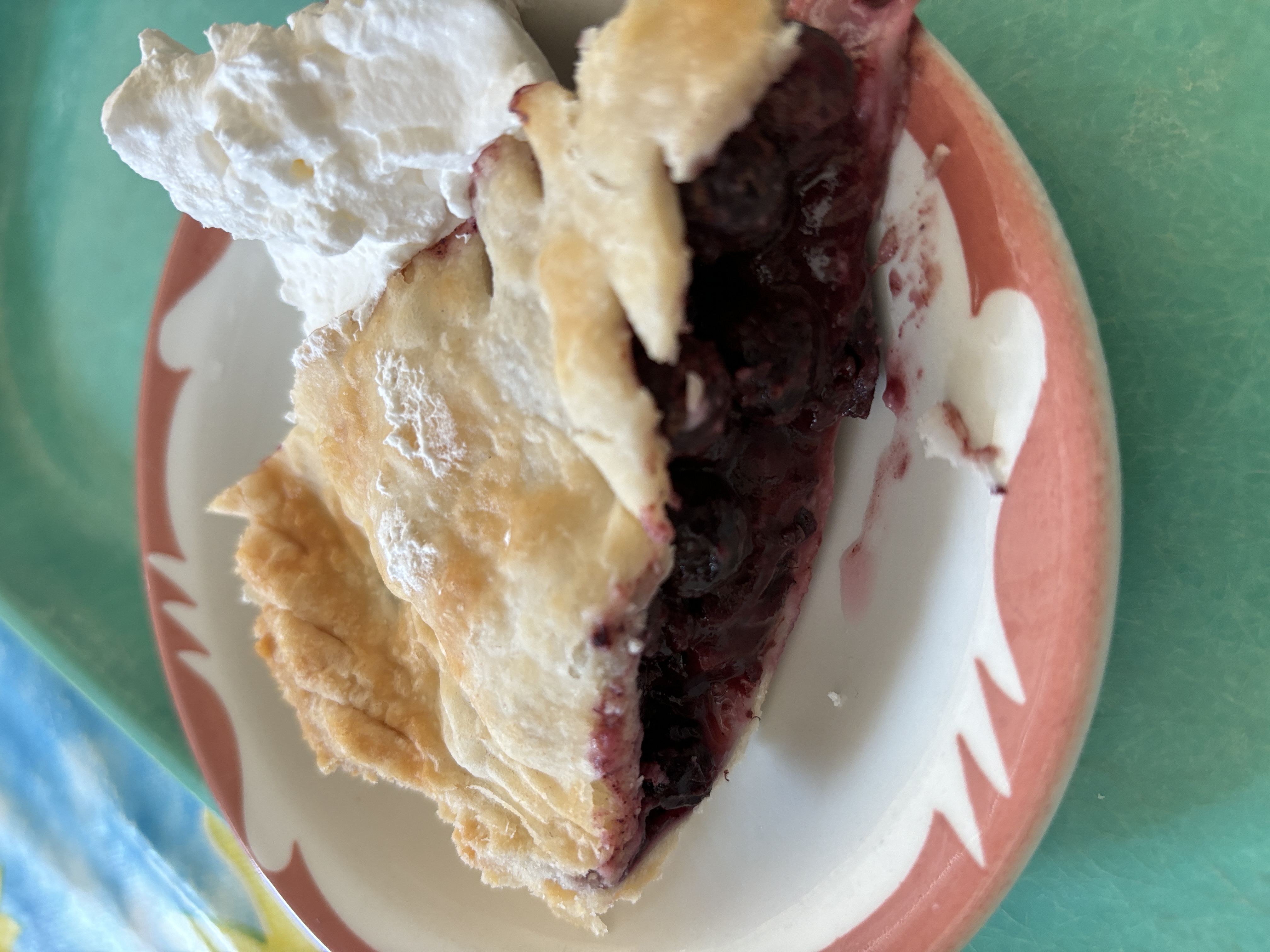 A wedge of pie with purple berries, on a 1960s style diner plate